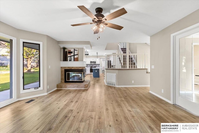 16324 Chicago St, Omaha, NE 68118 - unfurnished living room featuring light wood finished floors, stairs, a ceiling fan, baseboards, and a glass covered fireplace