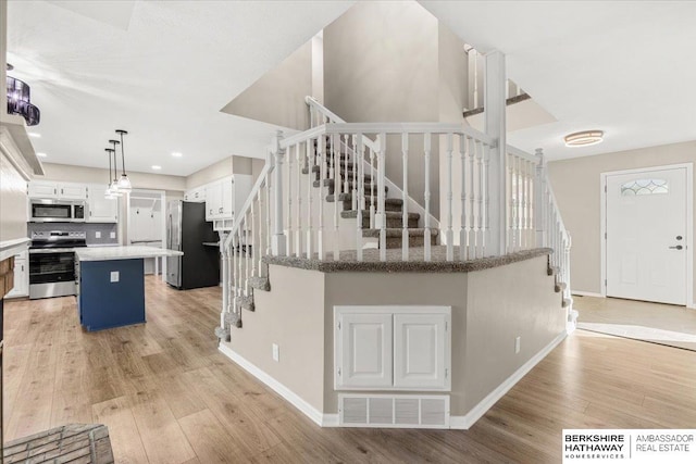 16324 Chicago St, Omaha, NE 68118 - kitchen featuring appliances with stainless steel finishes, a center island, light wood-style flooring, baseboards, and white cabinets