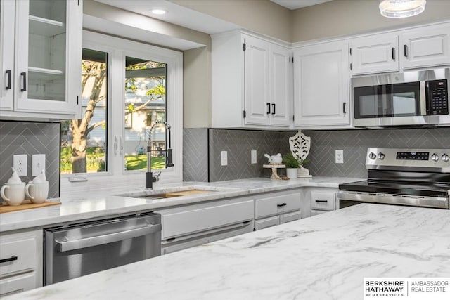 16324 Chicago St, Omaha, NE 68118 - kitchen with stainless steel appliances, a sink, decorative backsplash, white cabinetry, and light stone countertops