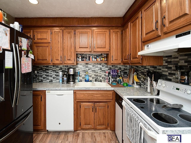 2103 Randall Dr, Bellevue, NE 68005 - kitchen with white appliances, under cabinet range hood, a sink, brown cabinetry, and light countertops
