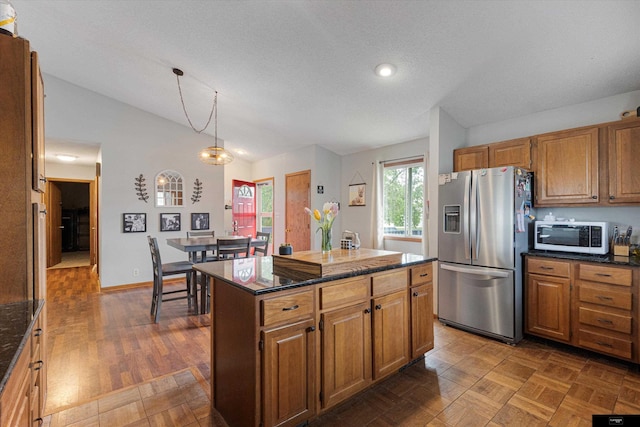 2706 Overlook Cir, Plattsmouth, NE 68048 - kitchen with stainless steel refrigerator with ice dispenser, lofted ceiling, brown cabinetry, decorative light fixtures, and dark stone countertops