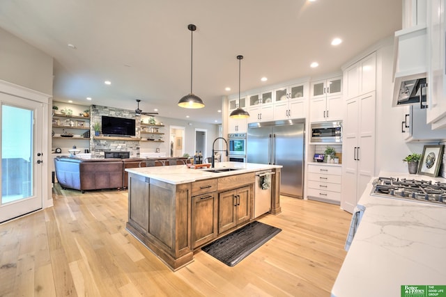 12369 Cooper St, Papillion, NE 68046 - kitchen featuring built in appliances, light wood-style flooring, a stone fireplace, white cabinetry, and recessed lighting