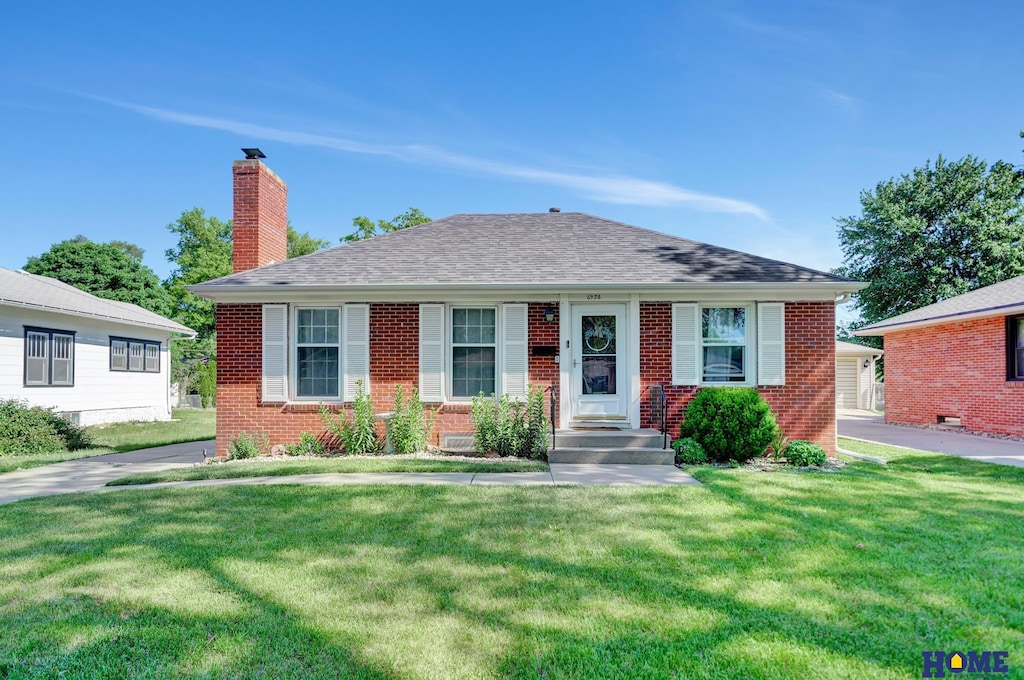 6938 Ballard Ave, Lincoln, NE 68507 - bungalow-style home with brick siding, a chimney, a front yard, and roof with shingles