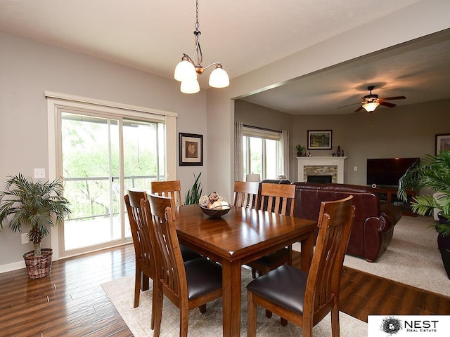 7521 Exbury Rd, Lincoln, NE 68516 - dining room featuring dark wood-style flooring, a chandelier, a fireplace, and ceiling fan