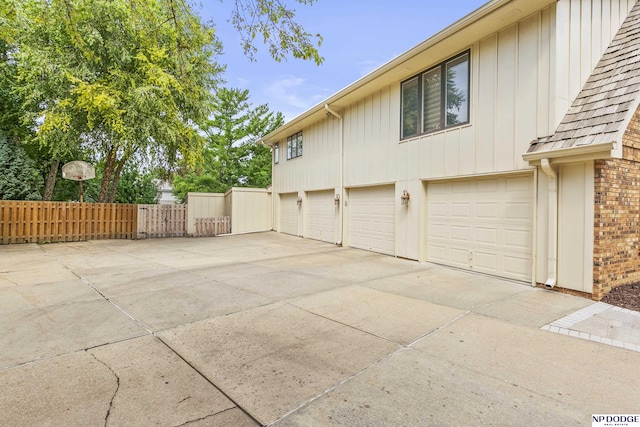 9826 Harney Pkwy N, Omaha, NE 68114 - view of side of property with concrete driveway, a garage, board and batten siding, and brick siding
