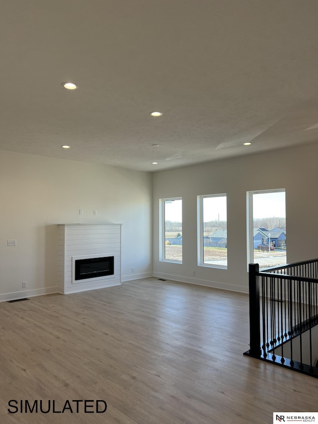1231 SW 36th St, Lincoln, NE 68522 - unfurnished living room featuring wood finished floors, recessed lighting, baseboards, and a glass covered fireplace