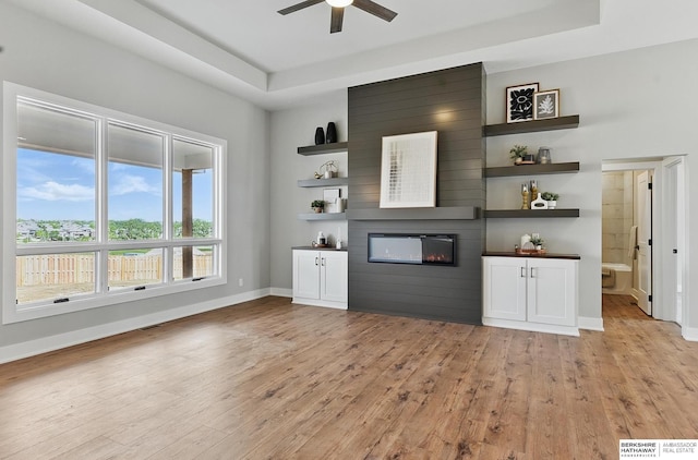 8218 N 167th Ave, Bennington, NE 68007 - unfurnished living room featuring light wood-type flooring, a large fireplace, a ceiling fan, and a tray ceiling