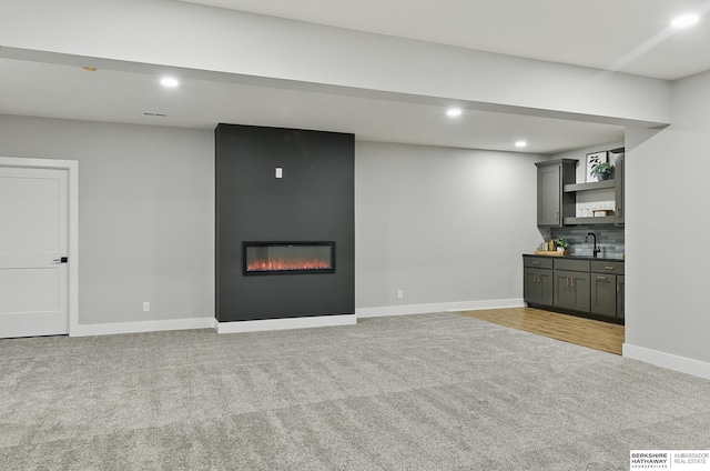 8218 N 167th Ave, Bennington, NE 68007 - unfurnished living room featuring light colored carpet, recessed lighting, a large fireplace, baseboards, and bar with sink
