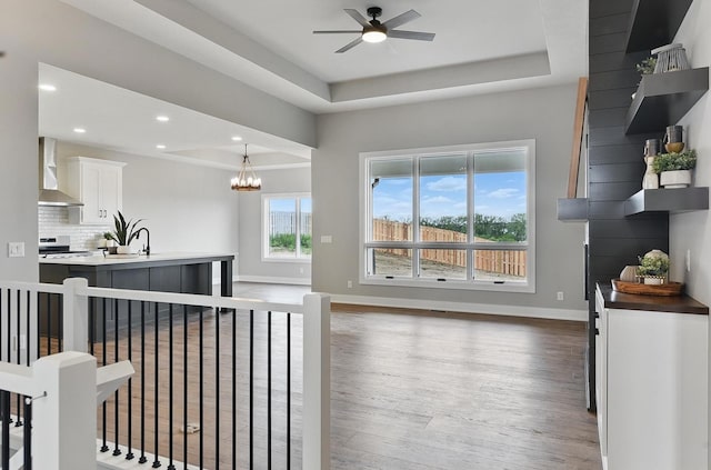 8218 N 167th Ave, Bennington, NE 68007 - living area featuring wood finished floors, a tray ceiling, a ceiling fan, baseboards, and a chandelier
