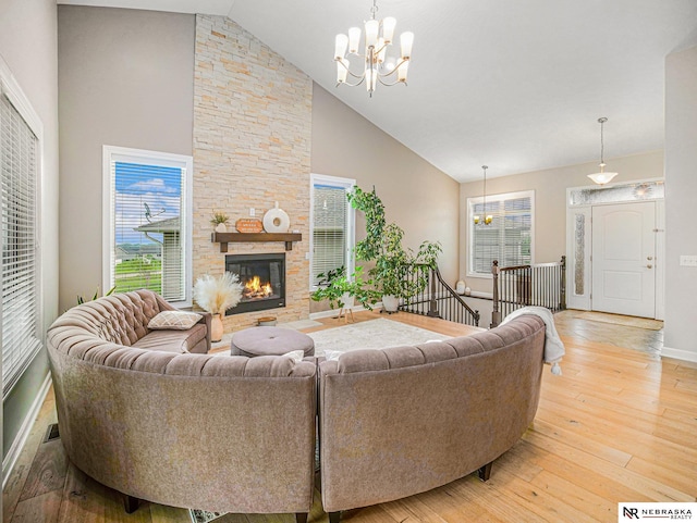 9656 White Pine Rd, Lincoln, NE 68505 - living area with a chandelier, high vaulted ceiling, light wood-type flooring, baseboards, and a stone fireplace
