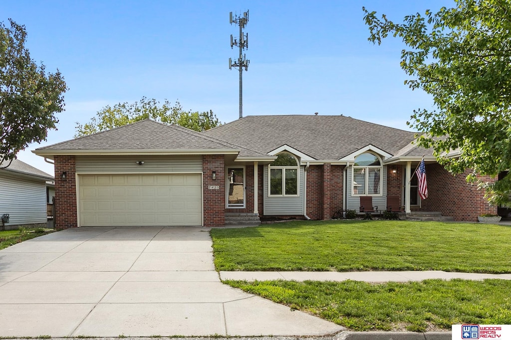 7425 S 28th St, Lincoln, NE 68516 - ranch-style home with a garage, driveway, a front yard, brick siding, and roof with shingles