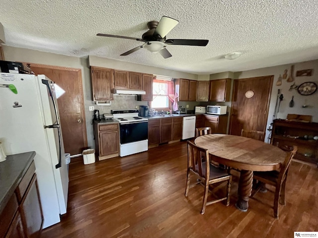 606 E 7th St, Valentine, NE 69201 - kitchen featuring white appliances, under cabinet range hood, dark wood finished floors, a ceiling fan, and a textured ceiling