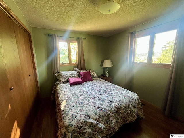 606 E 7th St, Valentine, NE 69201 - bedroom featuring dark wood-type flooring, a closet, a textured ceiling, and baseboards