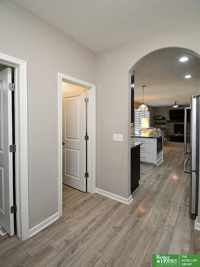 7968 N 163rd Ave, Bennington, NE 68007 - hall featuring arched walkways, light wood finished floors, a textured ceiling, baseboards, and recessed lighting