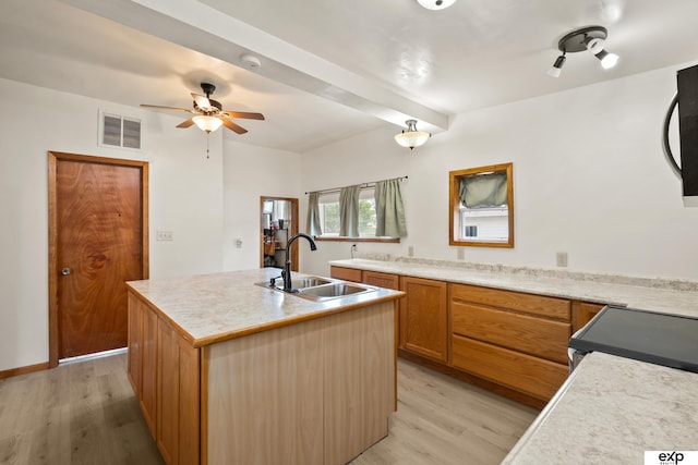 1346 G St, Pawnee City, NE 68420 - kitchen with a sink, light wood-style flooring, an island with sink, light countertops, and beamed ceiling