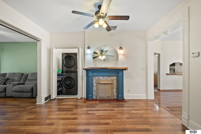 1346 G St, Pawnee City, NE 68420 - living area featuring stacked washer / drying machine, a ceiling fan, a fireplace, wood finished floors, and baseboards