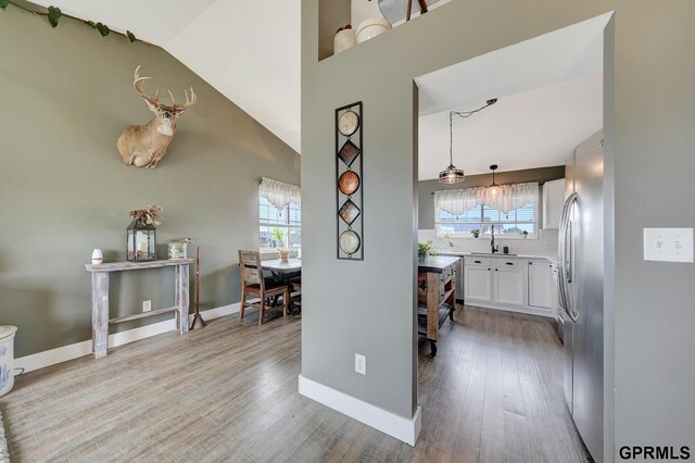 4441 W Hub Hall Dr, Lincoln, NE 68528 - hallway with light wood-type flooring, baseboards, a sink, and high vaulted ceiling