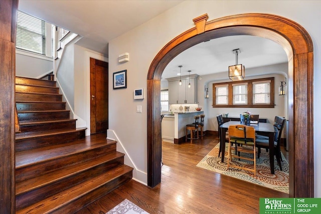 2028 N 55th St, Omaha, NE 68104 - dining room with arched walkways, dark wood-style flooring, stairs, and baseboards