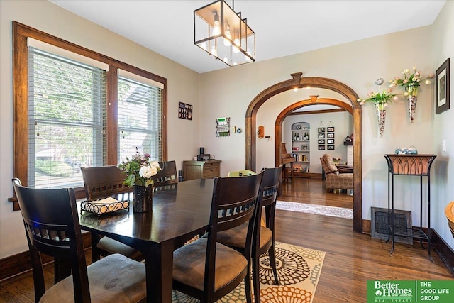 2028 N 55th St, Omaha, NE 68104 - dining area featuring arched walkways, dark wood-style flooring, a chandelier, and baseboards