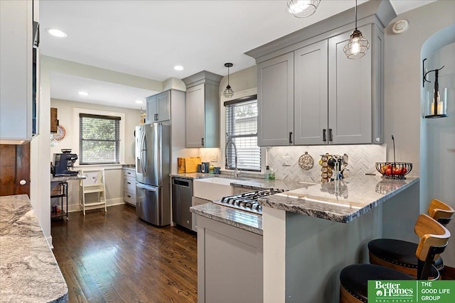 2028 N 55th St, Omaha, NE 68104 - kitchen with appliances with stainless steel finishes, a sink, a peninsula, light stone countertops, and recessed lighting