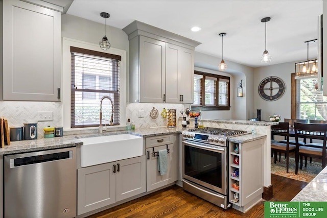 2028 N 55th St, Omaha, NE 68104 - kitchen featuring appliances with stainless steel finishes, a sink, a peninsula, backsplash, and dark wood-type flooring