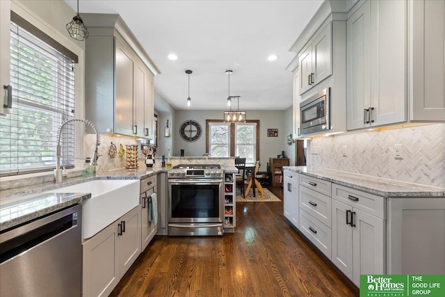 2028 N 55th St, Omaha, NE 68104 - kitchen featuring stainless steel appliances, a peninsula, light stone countertops, recessed lighting, and dark wood finished floors