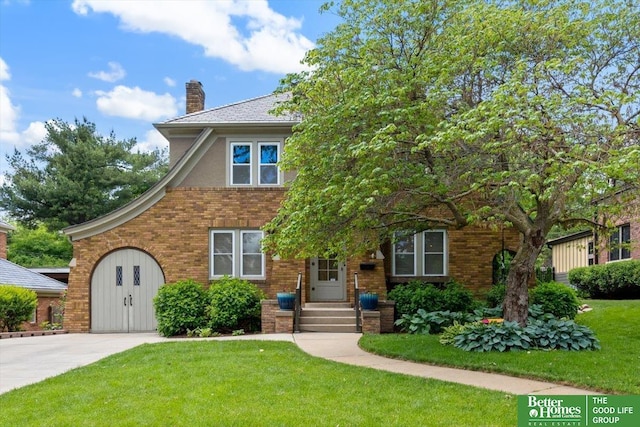 2028 N 55th St, Omaha, NE 68104 - view of front of house with a chimney, a front lawn, brick siding, and concrete driveway