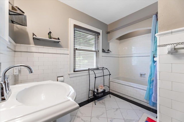 2028 N 55th St, Omaha, NE 68104 - full bath featuring tiled shower / bath combo, marble look tiles, a sink, tile walls, and a wainscoted wall