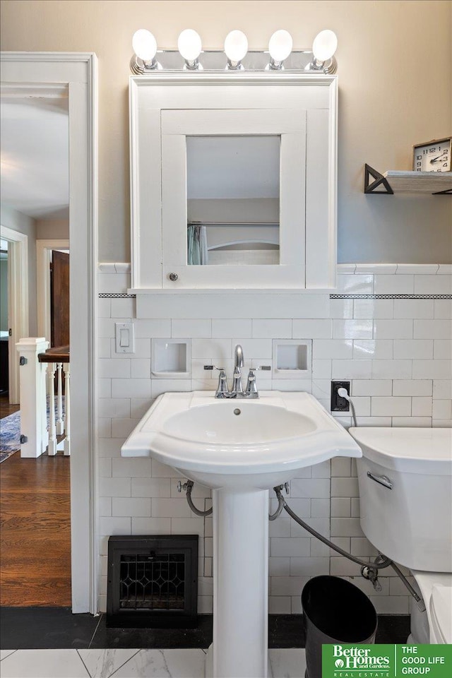 2028 N 55th St, Omaha, NE 68104 - half bathroom featuring tile walls, toilet, and wainscoting