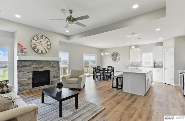 6320 Harvest Dr, Papillion, NE 68133 - living area featuring light wood-style flooring, a ceiling fan, a fireplace, recessed lighting, and a chandelier