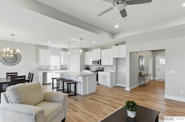 6320 Harvest Dr, Papillion, NE 68133 - living room featuring ceiling fan, a chandelier, light wood-style floors, recessed lighting, and baseboards