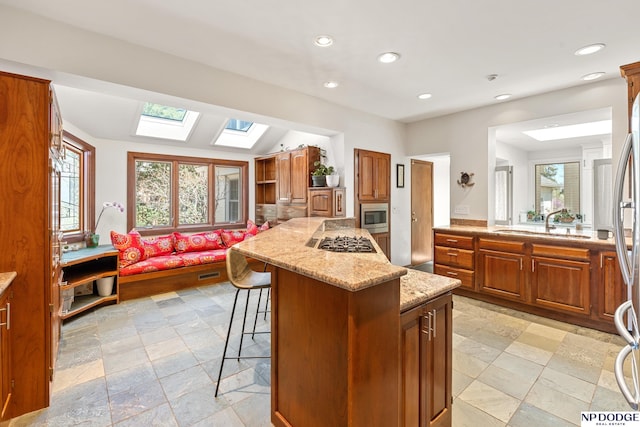 423 Fairacres Rd, Omaha, NE 68132 - kitchen featuring a skylight, stainless steel appliances, light stone counters, a kitchen bar, and a center island