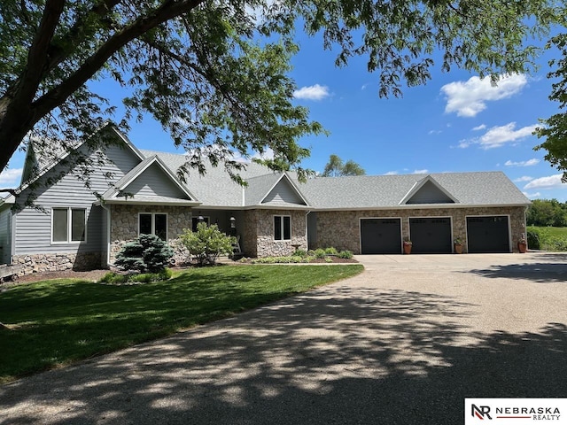 10955 N 58th Plz, Omaha, NE 68152 - view of front of house featuring stone siding, an attached garage, a front lawn, and concrete driveway
