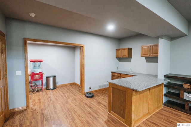 10955 N 58th Plz, Omaha, NE 68152 - kitchen with light wood-type flooring, a peninsula, brown cabinetry, and a sink