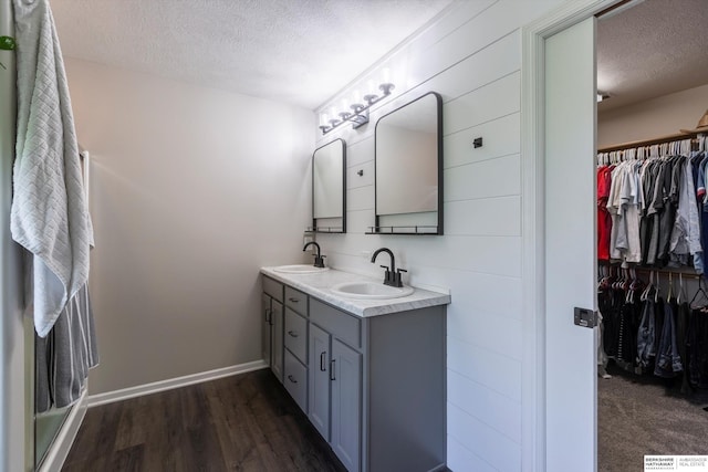15210 Craig Cir, Bennington, NE 68007 - bathroom with a textured ceiling, a walk in closet, double vanity, wood finished floors, and baseboards