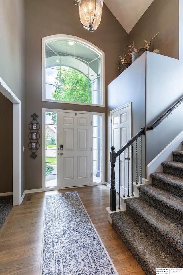 15210 Craig Cir, Bennington, NE 68007 - entryway featuring high vaulted ceiling, stairway, wood finished floors, baseboards, and a chandelier