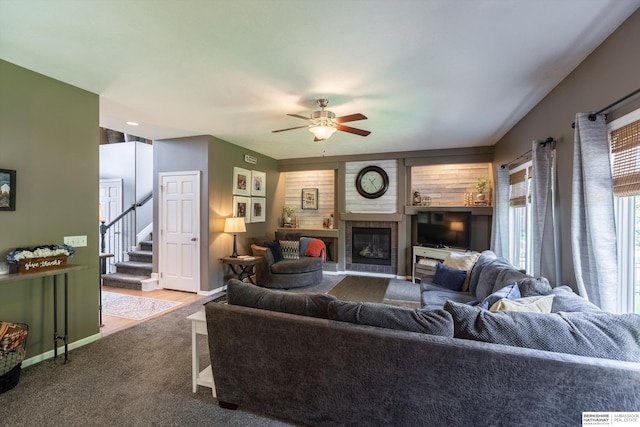 15210 Craig Cir, Bennington, NE 68007 - carpeted living room with ceiling fan, a glass covered fireplace, stairs, and baseboards