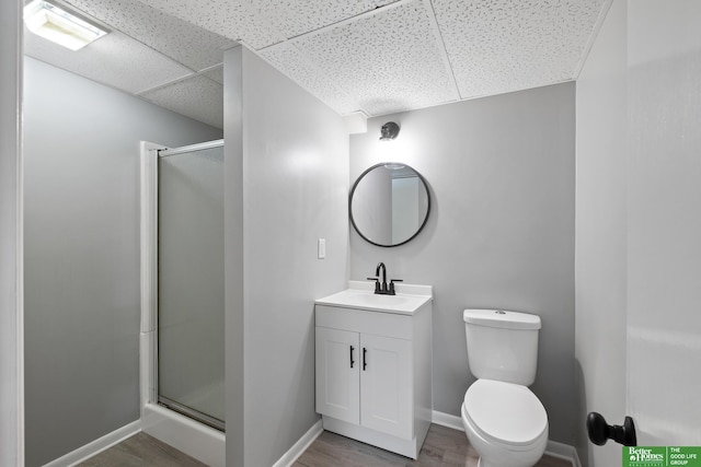 3501 Leawood Dr, Bellevue, NE 68123 - bathroom featuring vanity, a stall shower, a paneled ceiling, toilet, and wood finished floors