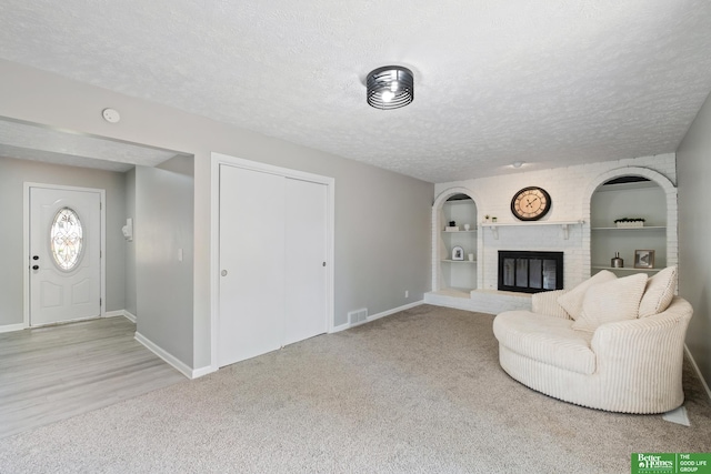 3501 Leawood Dr, Bellevue, NE 68123 - living room featuring baseboards, carpet floors, a textured ceiling, a brick fireplace, and built in features