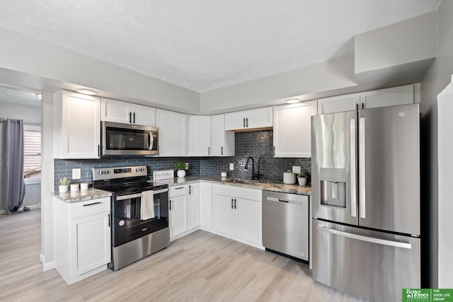 3501 Leawood Dr, Bellevue, NE 68123 - kitchen with stainless steel appliances, a sink, light stone countertops, light wood-style floors, and a textured ceiling