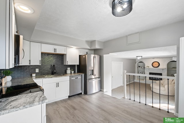 3501 Leawood Dr, Bellevue, NE 68123 - kitchen with appliances with stainless steel finishes, a sink, light wood-style flooring, decorative backsplash, and white cabinets