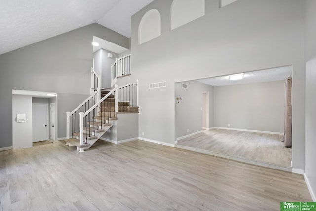 3501 Leawood Dr, Bellevue, NE 68123 - unfurnished living room featuring high vaulted ceiling, wood finished floors, stairs, and baseboards