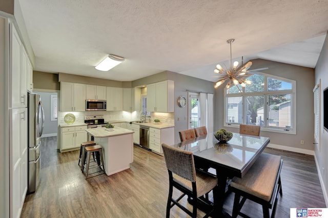 7627 S 38th St, Lincoln, NE 68516 - dining room with wood finished floors, baseboards, vaulted ceiling, a chandelier, and a textured ceiling
