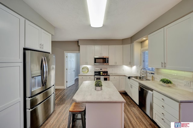 7627 S 38th St, Lincoln, NE 68516 - kitchen featuring appliances with stainless steel finishes, a center island, a sink, white cabinetry, and light countertops