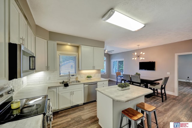 7627 S 38th St, Lincoln, NE 68516 - kitchen with stainless steel appliances, a sink, decorative backsplash, a kitchen bar, and dark wood finished floors