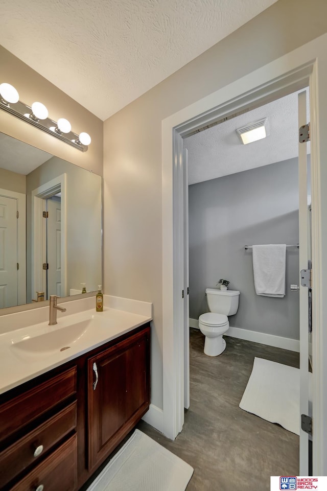 7627 S 38th St, Lincoln, NE 68516 - bathroom featuring vanity, baseboards, toilet, a textured ceiling, and concrete flooring