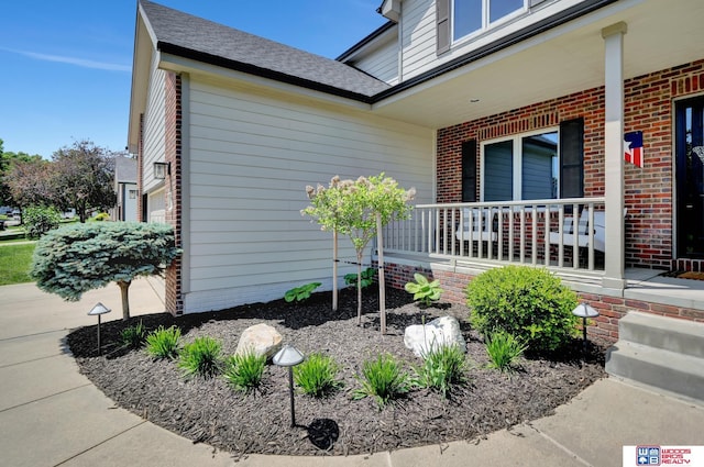 7627 S 38th St, Lincoln, NE 68516 - view of side of property featuring covered porch, brick siding, and a shingled roof
