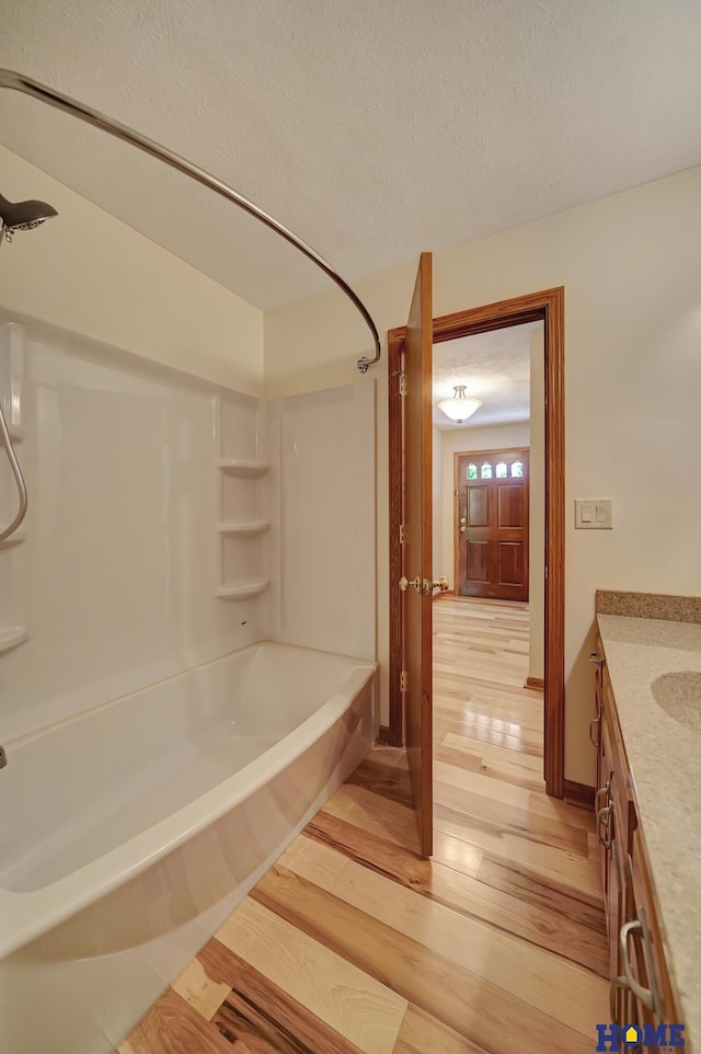 4801 S 72nd St, Lincoln, NE 68516 - bathroom featuring wood finished floors, washtub / shower combination, vanity, and a textured ceiling
