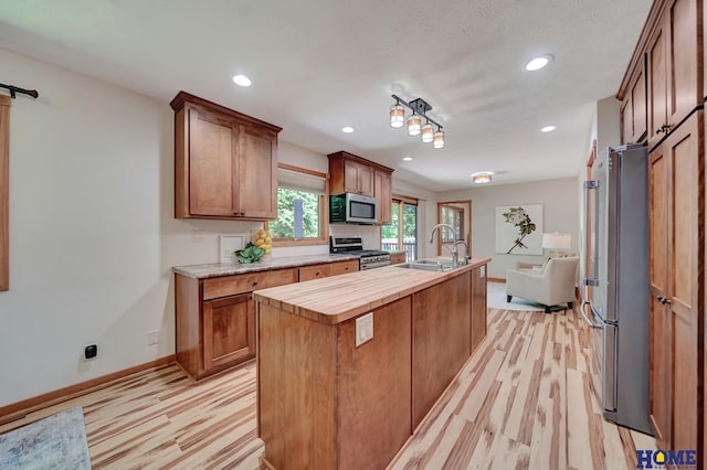 4801 S 72nd St, Lincoln, NE 68516 - kitchen featuring stainless steel appliances, a center island with sink, wood counters, baseboards, and a sink