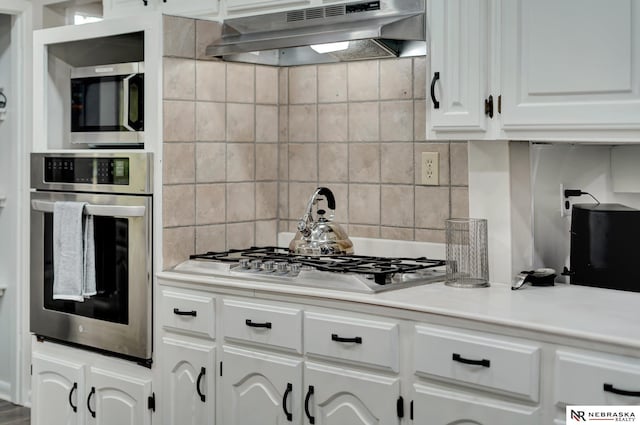 6844 Laurent Cir, Lincoln, NE 68526 - kitchen featuring appliances with stainless steel finishes, under cabinet range hood, white cabinets, decorative backsplash, and light countertops